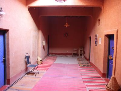 The image shows the interior of a building with terracotta-colored walls, bright blue doors, and striped rugs on the floor, with a filename referencing "Ait Ben Haddou".