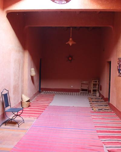 The image shows the interior of a building with terracotta-colored walls, bright blue doors, and striped rugs on the floor, with a filename referencing "Ait Ben Haddou".