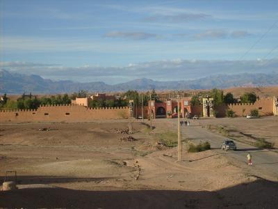 A wide shot of a large, fortified film set entrance with Egyptian-style statues and arches, set against a backdrop of desert terrain and mountains.
