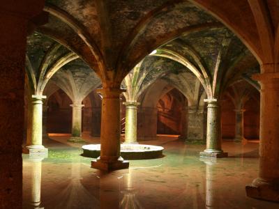An underground vaulted cistern with a grid of stone columns supporting ribbed vaults, filled with still water that reflects the architecture and light shafts from above.