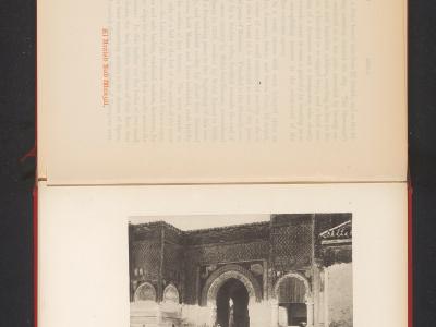 A black and white photograph printed on a page, depicting a large, ornate stone gate with a central archway and decorative tilework above, with several figures in traditional dress standing in the foreground; the page includes printed text and a capt