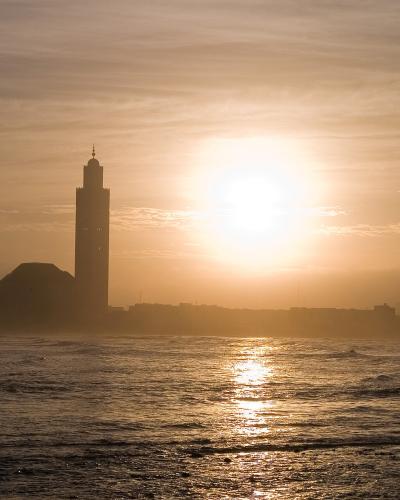 The minaret of the Hassan II Mosque silhouetted against the setting sun over the Atlantic, Casablanca