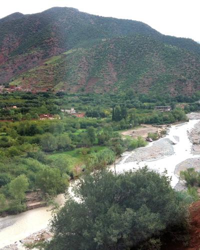 The Ourika river winding through the green Ourika Valley below the red slopes of the High Atlas